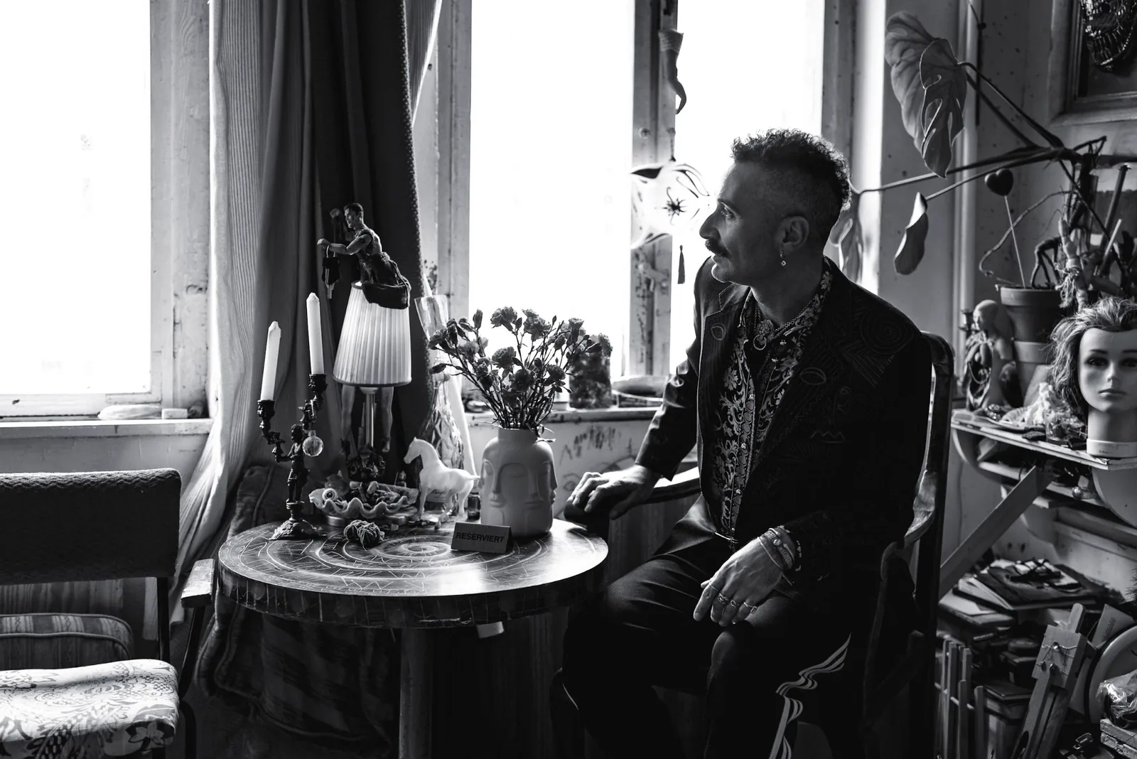 Marco Scola sitting by the window of his Kreuzberg studio, Atelier Attico, in black and white.