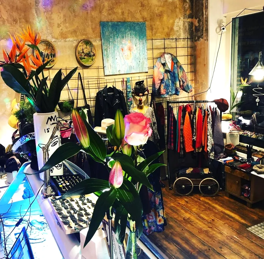 Inside the Matribal pop-up shop: painted jackets on a rail, jewellery on the counter, lilies in the foreground.